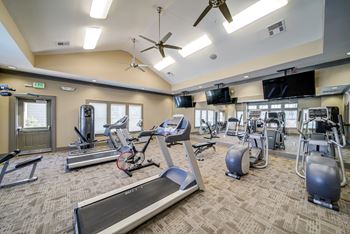 a gym with cardio equipment and flat screen televisions at the enclave at woodbridge apartments in at Avellan Springs Apartments, North Carolina